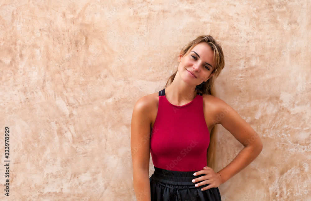 Cheerful beautiful young woman posing against wall on the street Cheerful beautiful young woman posing against wall on the street