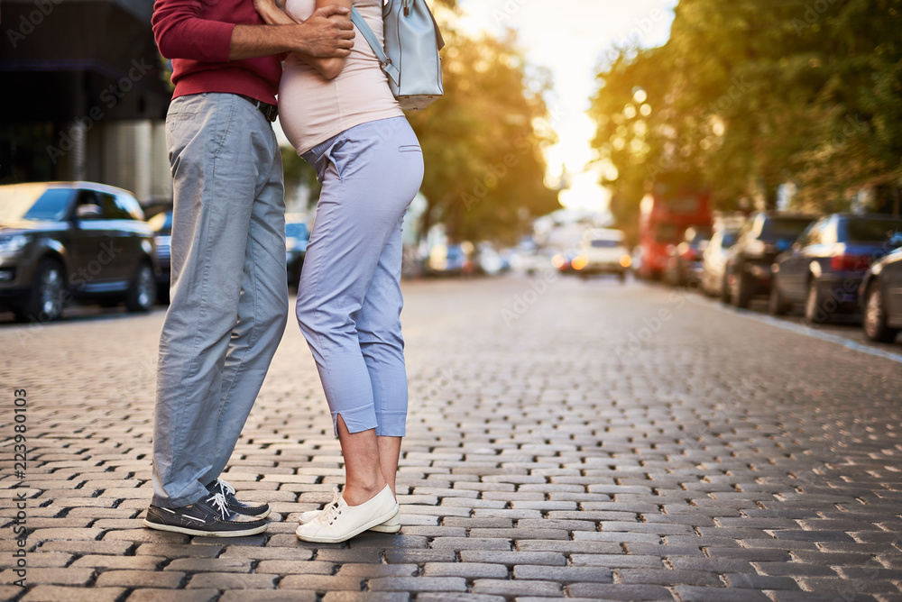 Love in the city. Cropped portrait of young pregnant woman snuggling up to loving husband while he pulling her closer Love in the city. Cropped portrait of young pregnant woman snuggling up to loving husband while he pulling her closer