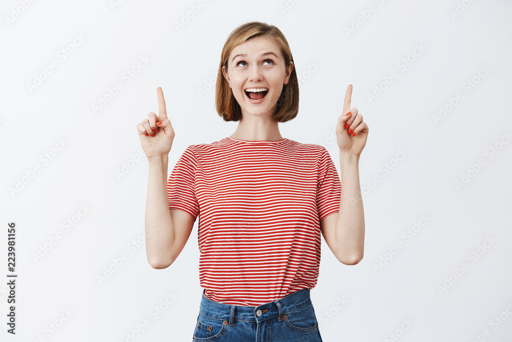 Soon I will be on plane on way to sea. Portrait of charming excited and thrilled cute fair-haired female with short haircut in striped t-shirt, looking and pointing up joyfully with dreamy expression Soon I will be on plane on way to sea. Portrait of charming excited and thrilled cute fair-haired female with short haircut in striped t-shirt, looking and pointing up joyfully with dreamy expression