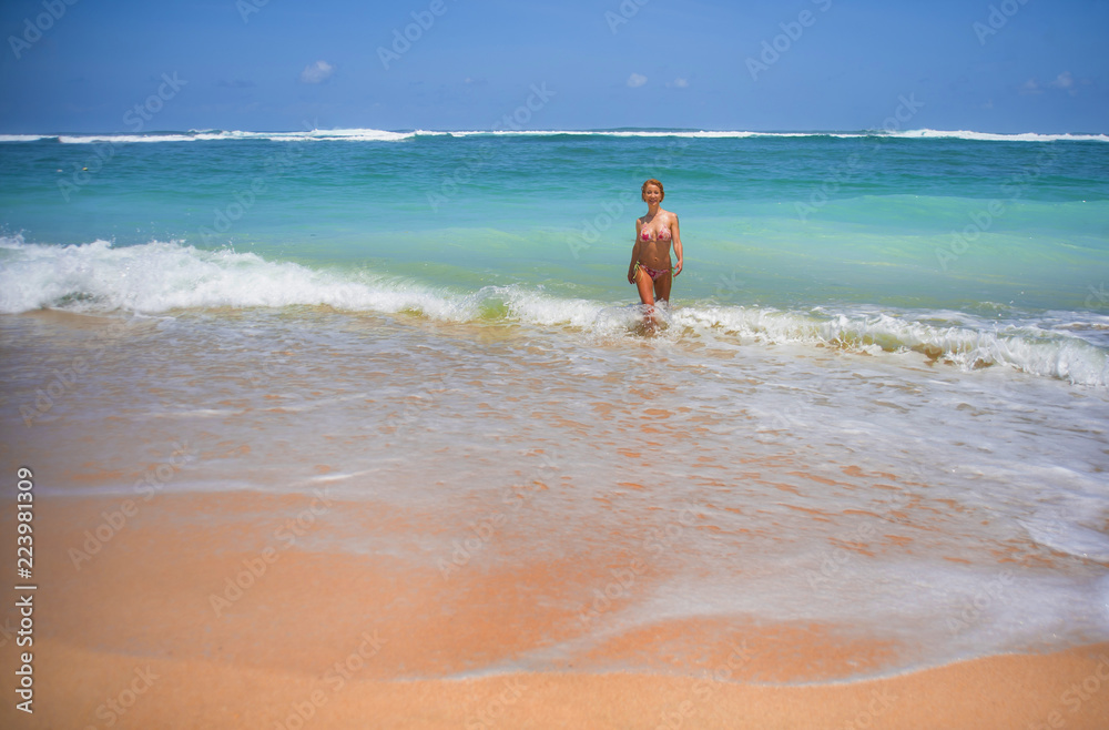 portrait of young attractive and happy woman in bikini posing at amazing beautiful desert beach with stunning sea color enjoying Summer holidays travel portrait of young attractive and happy woman in bikini posing at amazing beautiful desert beach with stunning sea color enjoying Summer holidays travel