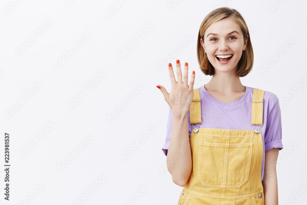 Obraz premium Look at my new manicure. Charming feminine carefree woman with fair short hair, showing number five with palms and smiling with interest and happiness, talking casually to camera, making video blog