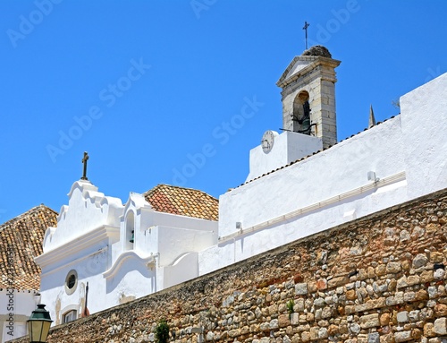 View of the rear of the 19th century city gateway wall and bell tower (Arco da Vila) in the city centre, Faro, Algarve, Portugal.
