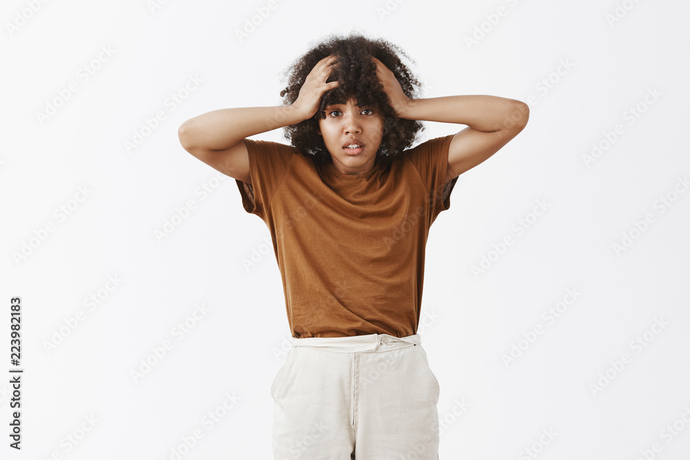Studio shot of silly and timid good-looking dark-skinned female student being upset and troubled having no idea how solve problems starting panic holding hands on head and frowning unhappy Studio shot of silly and timid good-looking dark-skinned female student being upset and troubled having no idea how solve problems starting panic holding hands on head and frowning unhappy