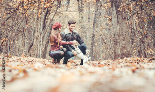 Woman and man petting the dog walking her in a colorful fall setting having fun in nature