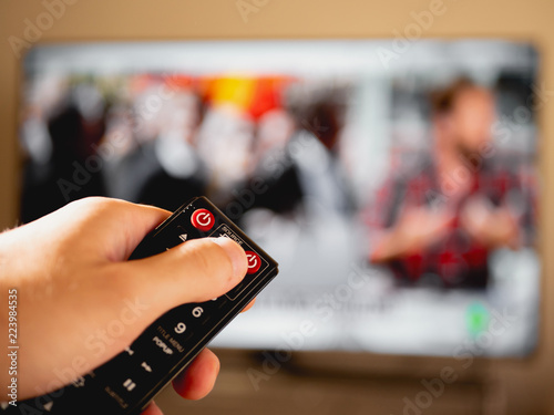 Remote control in hand watching news on television. Change channel. First person point of view. Concept