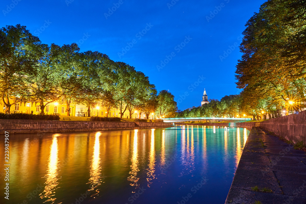 The night view of Aura river in Turku, Finland with a clock tower of cathedral and bridge on a background.                  