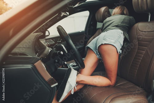 Female turning back to camera while looking at rear seat. She locating in contemporary car