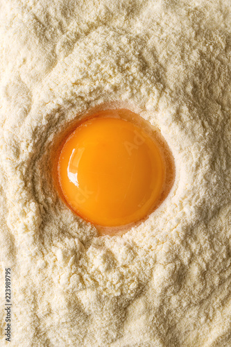 Ingredients for homemade italian pasta. Egg yolk in semolina flour. Flat lay, close up. Cooking koncept
