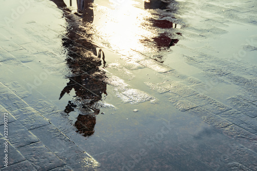 Silhouette of a person reflecting in a puddle after the rain.