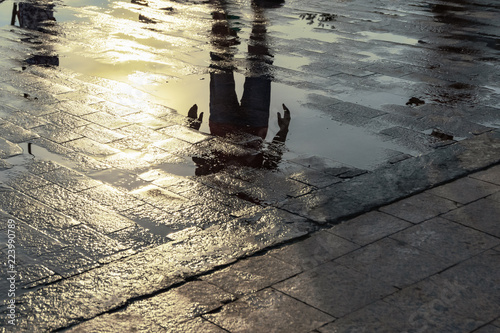 Silhouette of a person reflecting in a puddle after the rain.