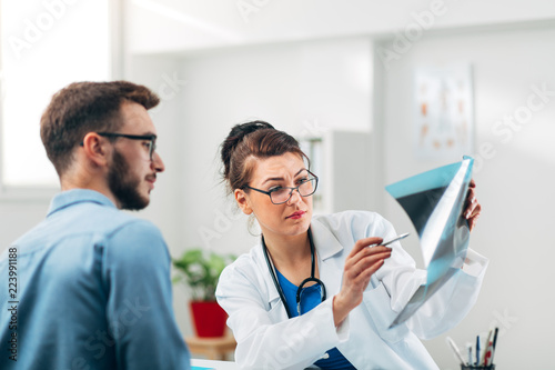 Portrait of Woman Doctor at her Medical Office Looking at X-Ray with Patient