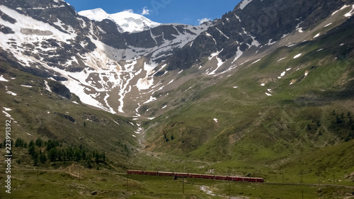 Red Swiss train of the Rhaetian Railways riding on the Bernina Pass (Graubunden, Switzerland) from and towards Italy. They own the largest network of all private railway operators in Switzerland.