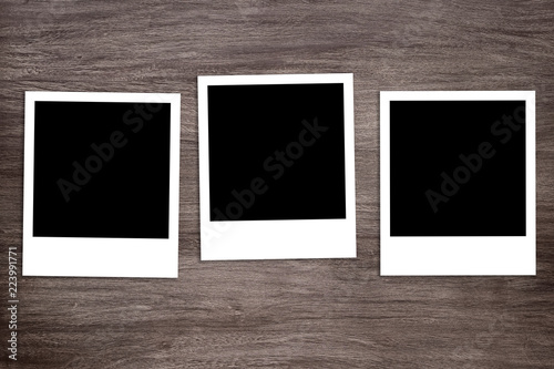 three blacked-out instant photo print templates on rustic wooden background