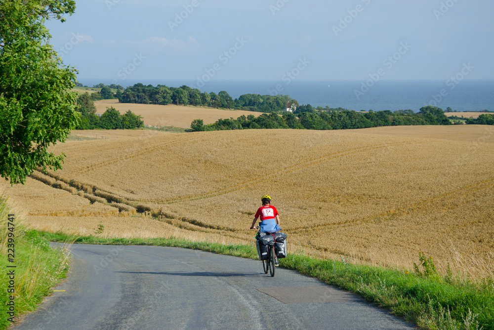 Lonely cycle tourist on the scenic countryside road in Denmark - island Mon (near Busene). Lonely cycle tourist on the scenic countryside road in Denmark - island Mon (near Busene).