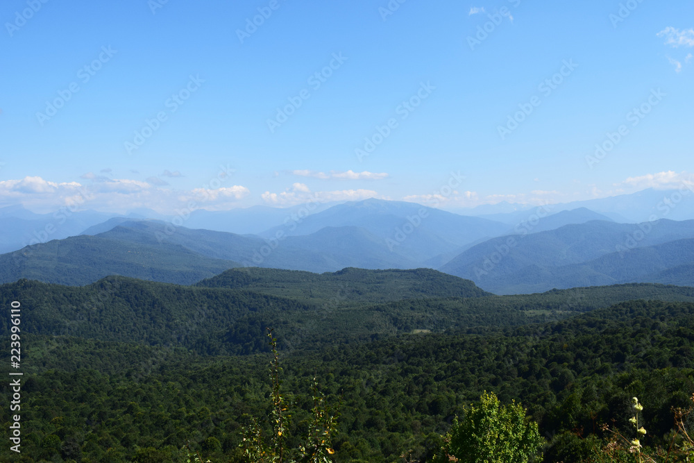 Green mountains and blue sky. Beautiful summer landscape with multilayered hills, fog and forest. Main Caucasian ridge, Adygea. Green mountains and blue sky. Beautiful summer landscape with multilayered hills, fog and forest. Main Caucasian ridge, Adygea.