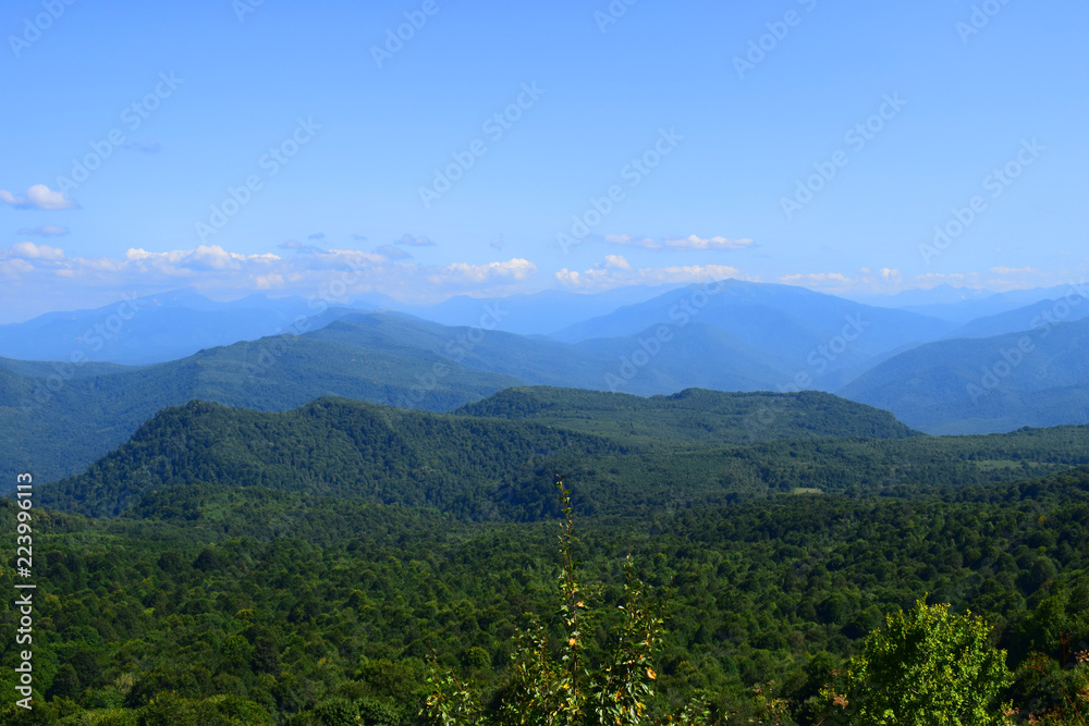 Green mountains and blue sky. Beautiful summer landscape with multilayered hills, fog and forest. Main Caucasian ridge, Adygea.