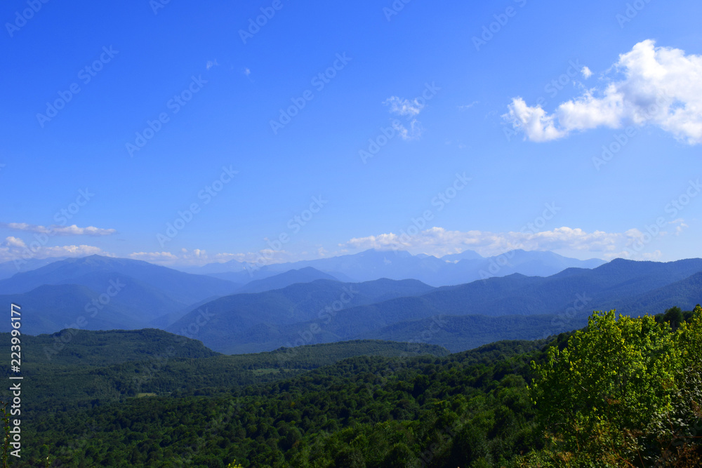 Green mountains and blue sky. Beautiful summer landscape with multilayered hills, fog and forest. Main Caucasian ridge, Adygea.