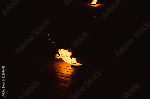 Fire burns in a stand on a cobbles of an ancient square at night, a holiday photo