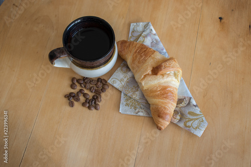 cup of coffee and croissant on wooden table