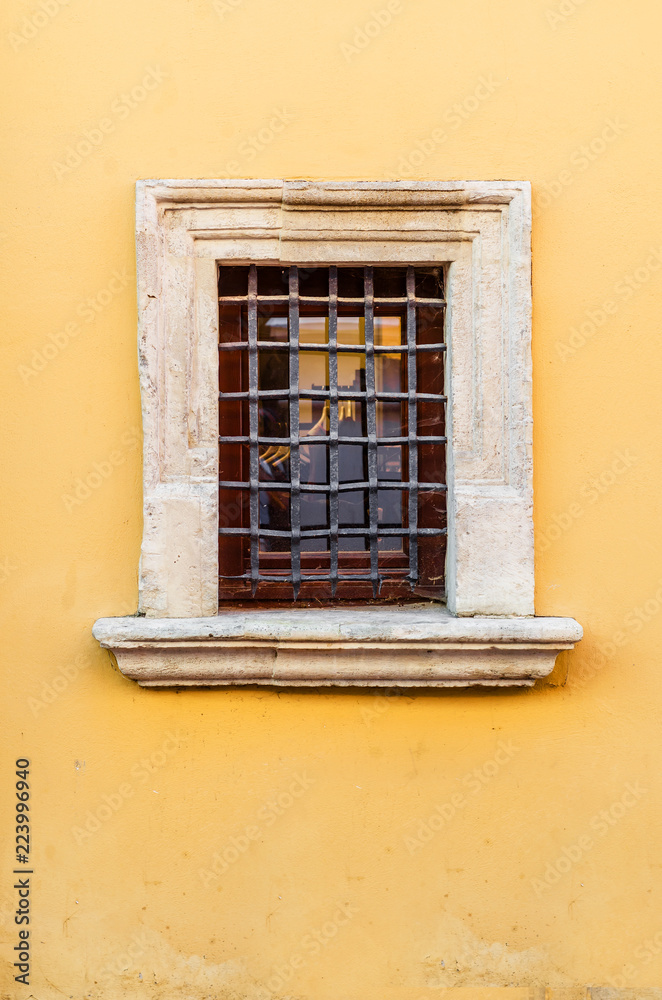 Obraz premium Small window with a metal grille in an old house