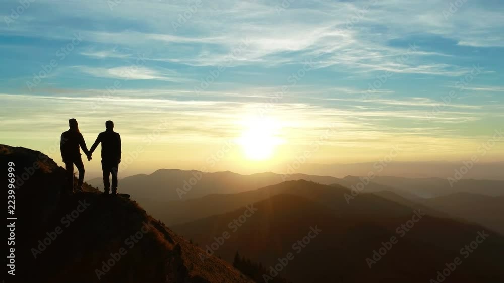 The man and a woman standing on the mountain and watching to a beautiful sunrise The man and a woman standing on the mountain and watching to a beautiful sunrise