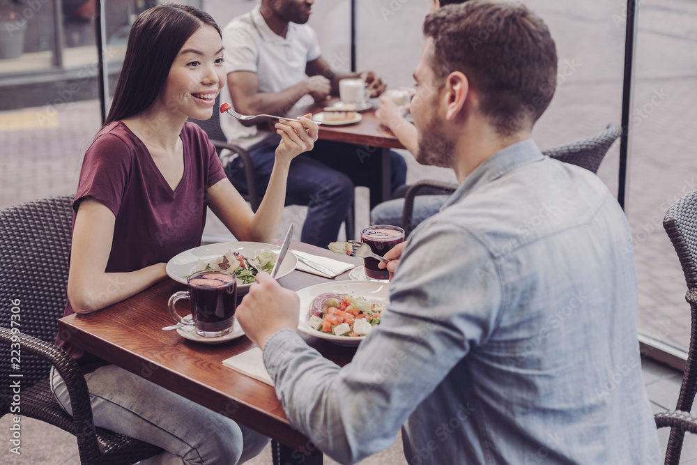 Healthy food. Delighted bearded man sitting opposite his girlfriend and going to eat his dinner Healthy food. Delighted bearded man sitting opposite his girlfriend and going to eat his dinner