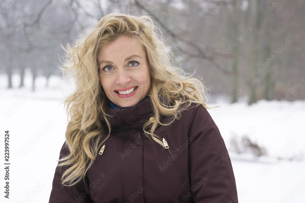 blond woman enjoying a winter walk through snow covered park