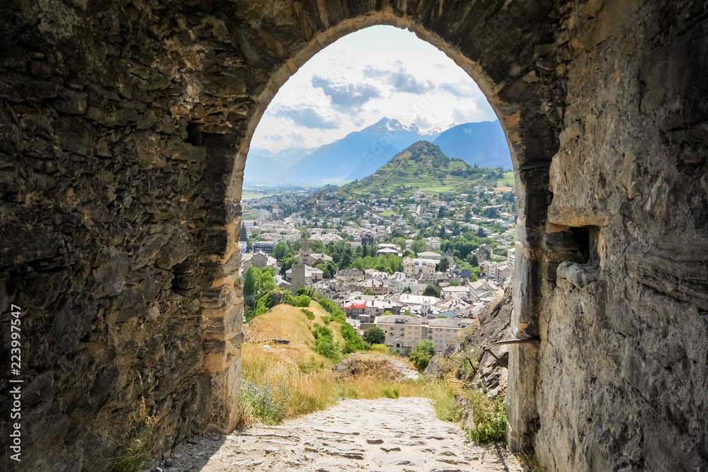When walking on the hills surrounding Sion towards the two castles (Valere, Tourbillon) one can enjoy vistas of this capital of Valais (Switzerland) when looking through ancient arches