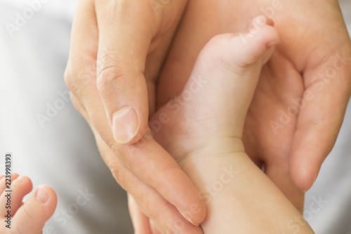 Mother's hands carefully keeping baby's foot with tenderness
