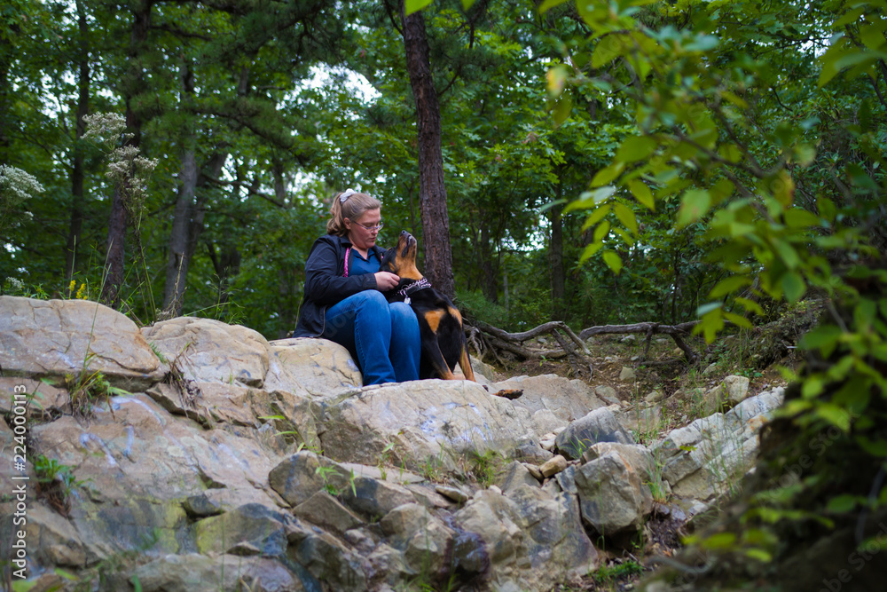 Woman Relaxing Along Hiking Path With Her Dog Friend And Guardian 