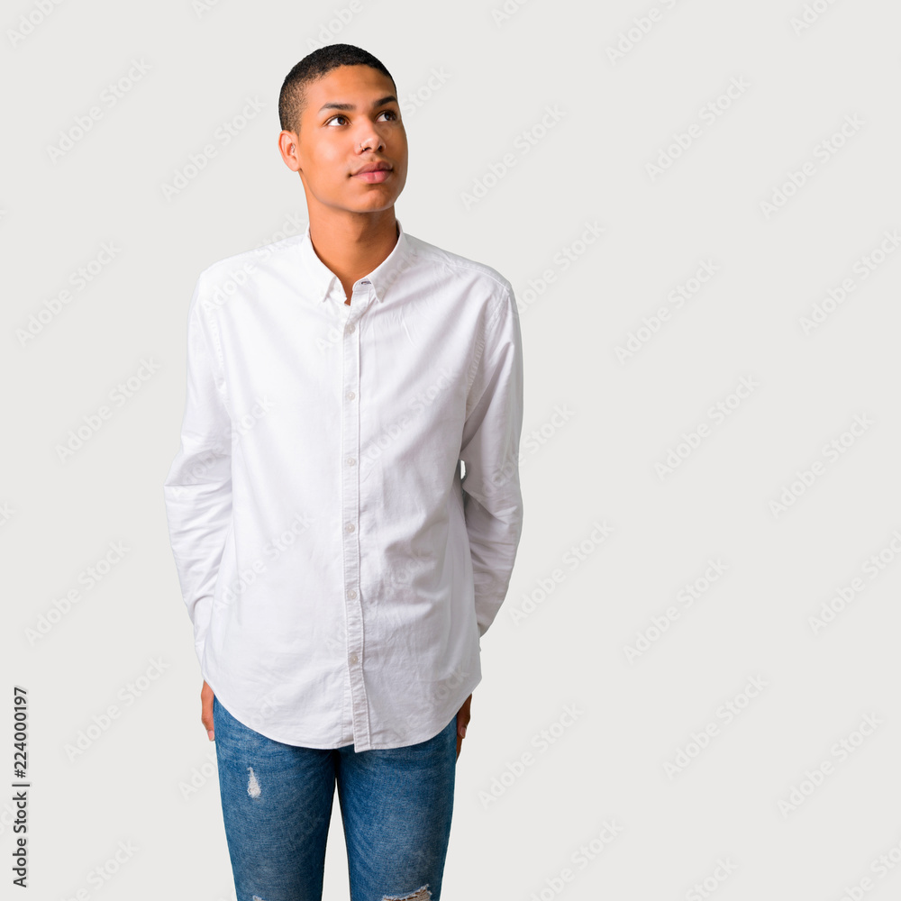 Young african american man stand and looking up with serious face on grey background Young african american man stand and looking up with serious face on grey background