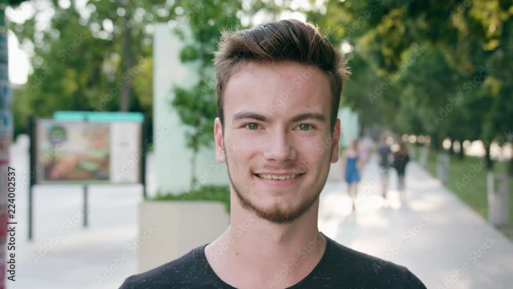 A young red-haired man with a beard smiling in the city street. Close-up shot. Soft focus A young red-haired man with a beard smiling in the city street. Close-up shot. Soft focus
