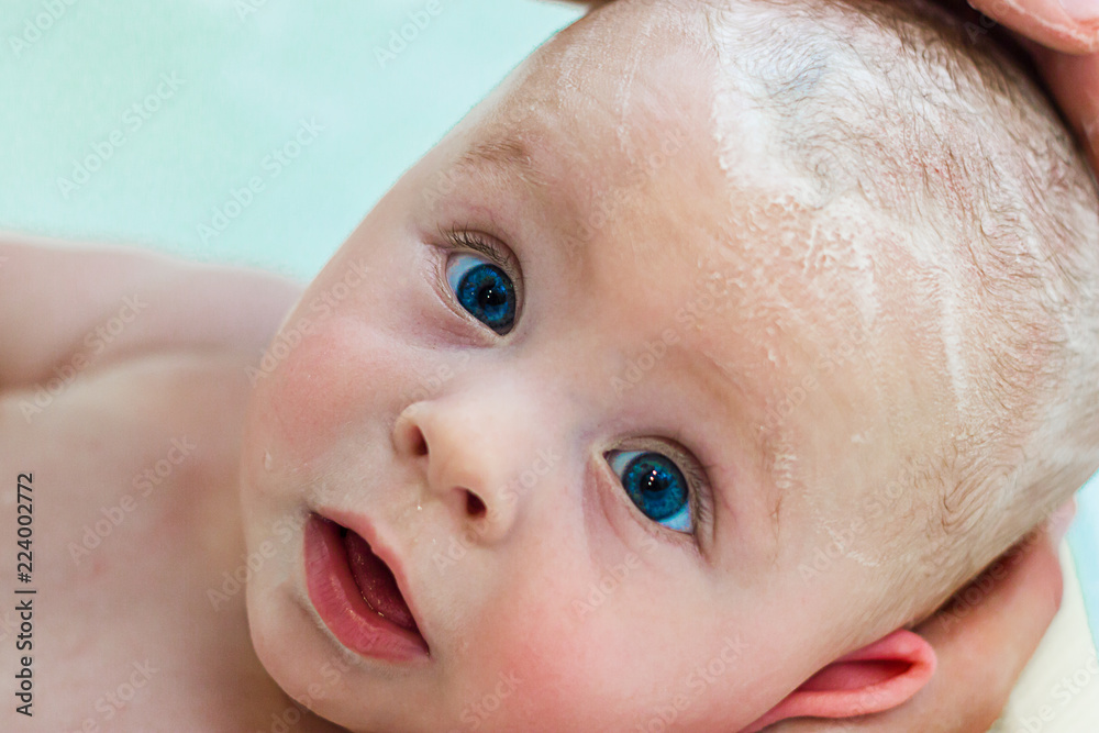 6 month baby boy taking a bath. Little child in a bathtub. Infant washing and bathing. Unrecognizable mother bathing her baby 6 month baby boy taking a bath. Little child in a bathtub. Infant washing and bathing. Unrecognizable mother bathing her baby
