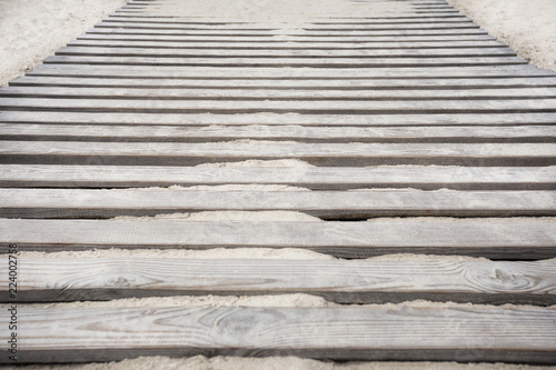 wooden bridge on the white sand on the beach near the sea photo