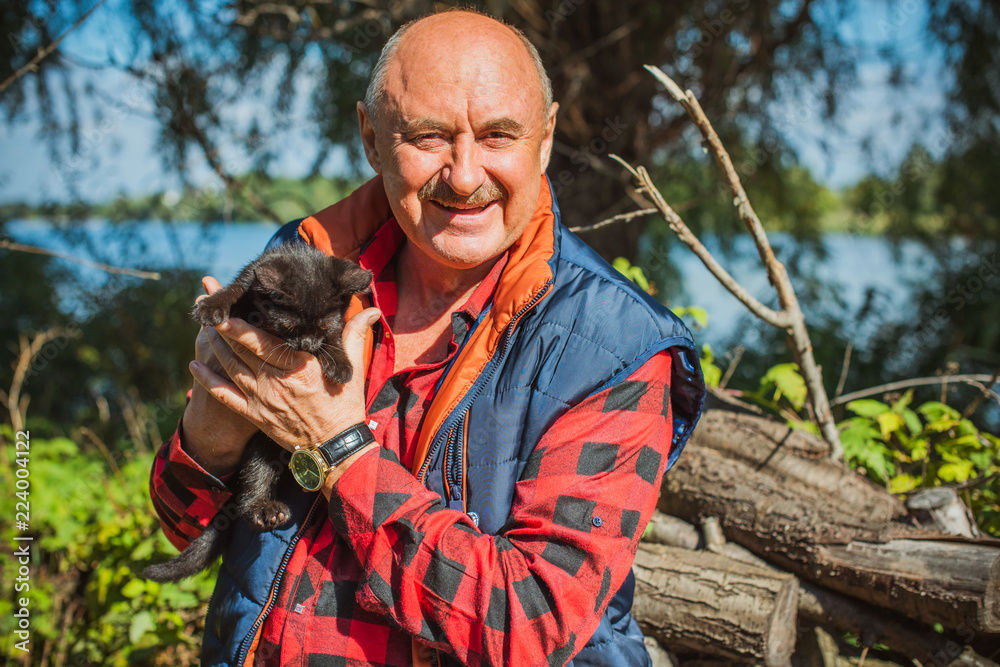 © T.Den_Team - Senior man with his pet little black kitty at home yard. American mature man with a cat. Concept of Life animals and human