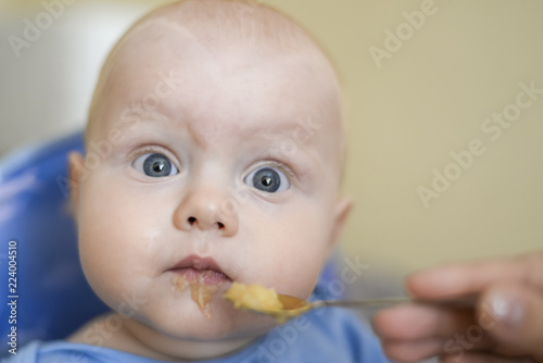 Mom feeds her son from a spoon with applesauce