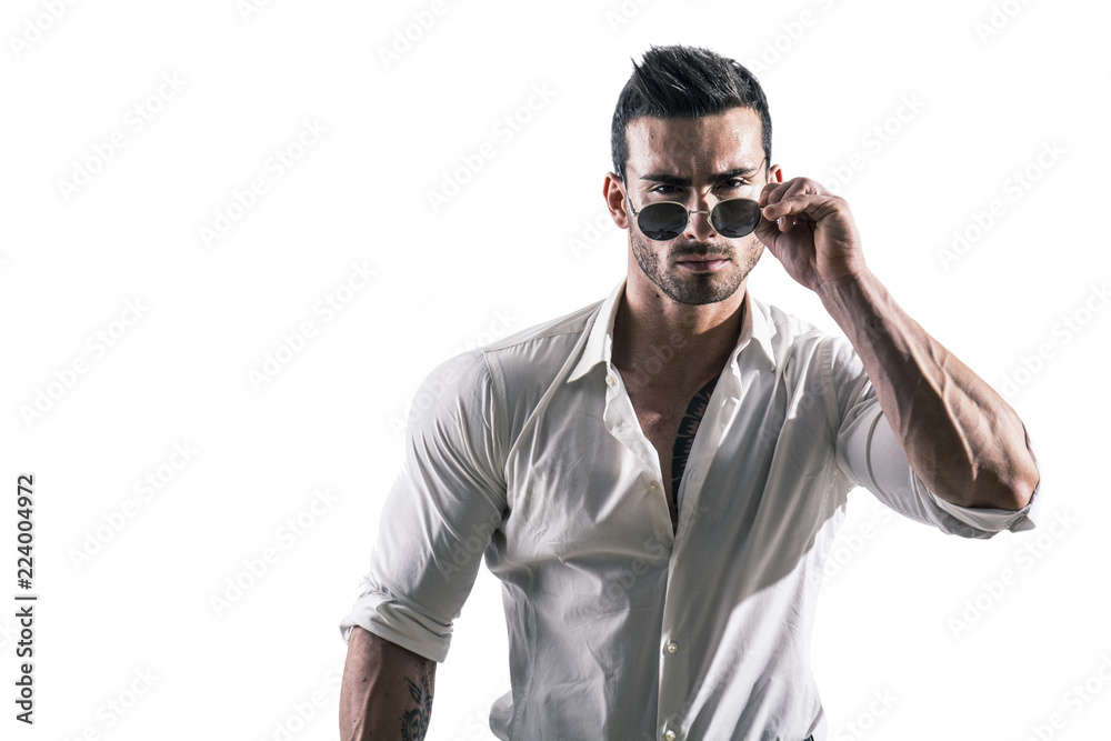 Portrait of brunette young man in white shirt and sunglasses, standing in studio shot isolated against white background. Full length photo Portrait of brunette young man in white shirt and sunglasses, standing in studio shot isolated against white background. Full length photo