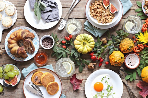  Thanksgiving Brunch. Autumn family breakfast or brunch set served on rustic wooden table. Overhead view, copy space