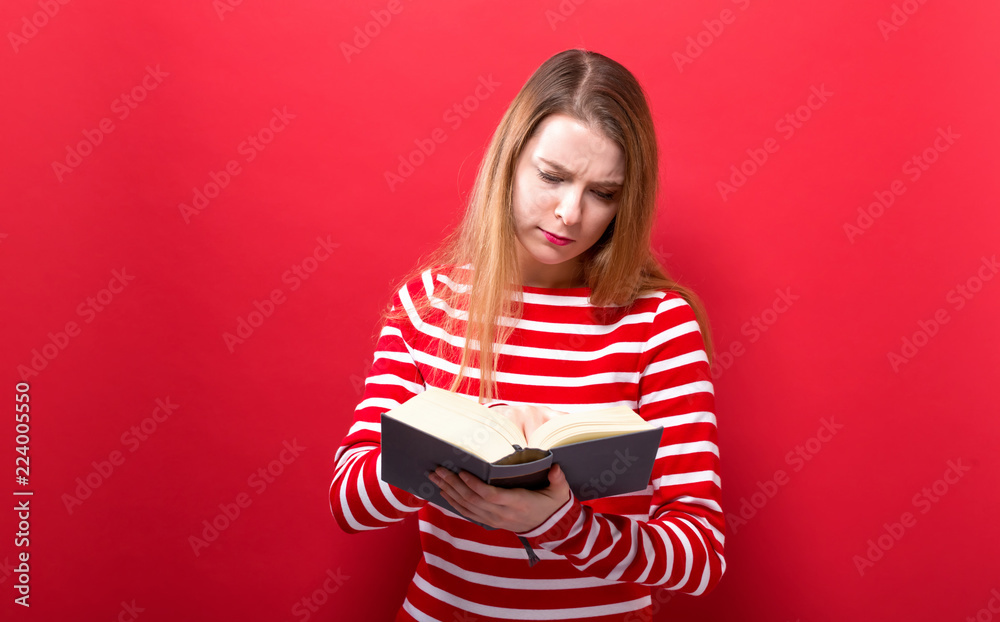 Young woman with a book on a solid background