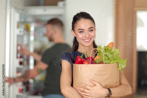 Young couple in the kitchen , woman with a bag of groceries shopping photo