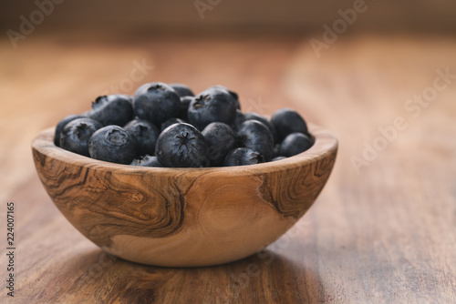 Fresh blueberries in wood bowl on table slightly toned