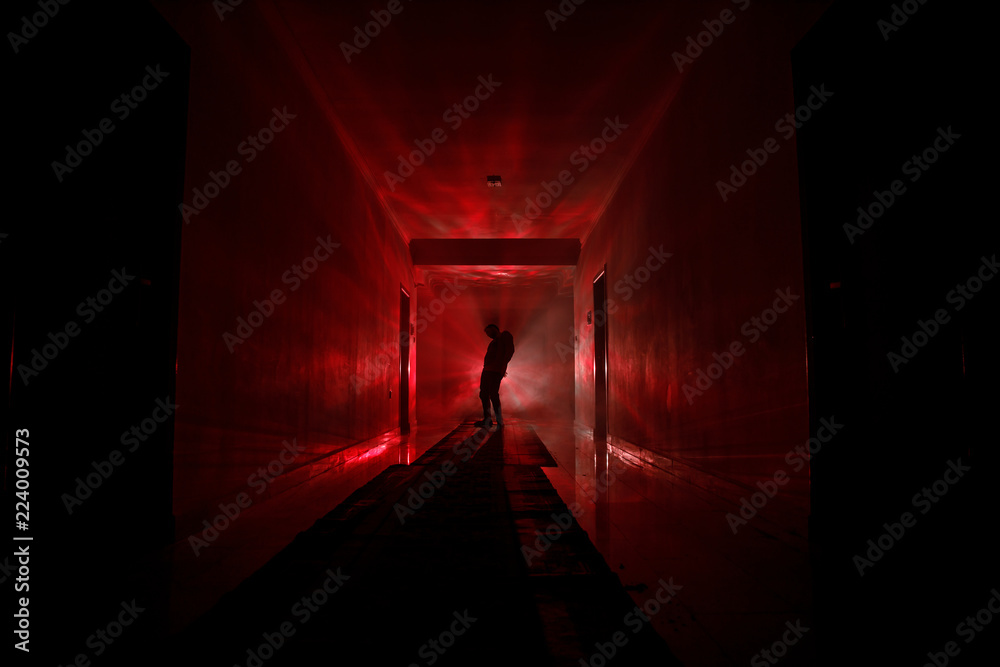 Creepy silhouette in the dark abandoned building. Dark corridor with cabinet doors and lights with silhouette of spooky horror person standing with different poses.