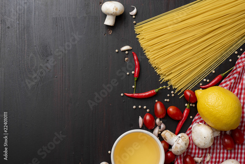 Spaghetti ingredients on black wooden desk, top view.