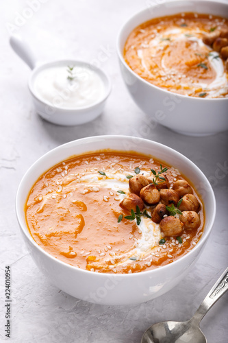 Carrot pumpkin soup with spicy chickpeas and sesame seeds on gray stone background copy space