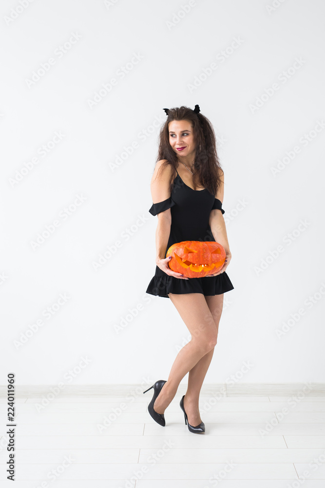 Cute gothic woman in halloween style clothes with pumpkin in hands Cute gothic woman in halloween style clothes with pumpkin in hands