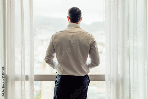 Businessman standing at hotel room window Free Download Businessman standing at hotel room window - GFXLoad