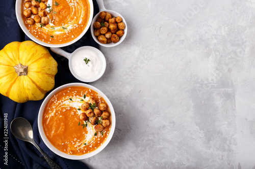 Carrot pumpkin soup with spicy chickpeas and sesame seeds on gray stone background copy space