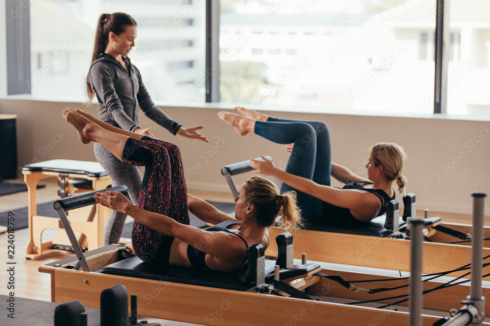 Pilates trainer instructing women at the gym - obrazy, fototapety, plakaty 