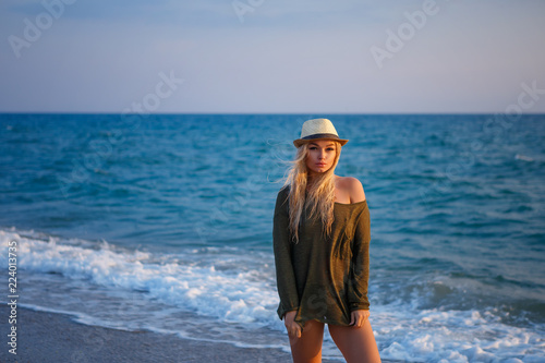 beautiful girl in hat by the sea at sunset