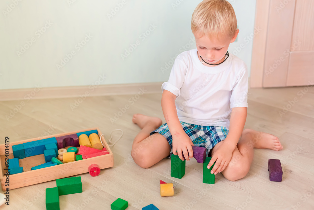 Cute little boy playing with colored wooden blocks